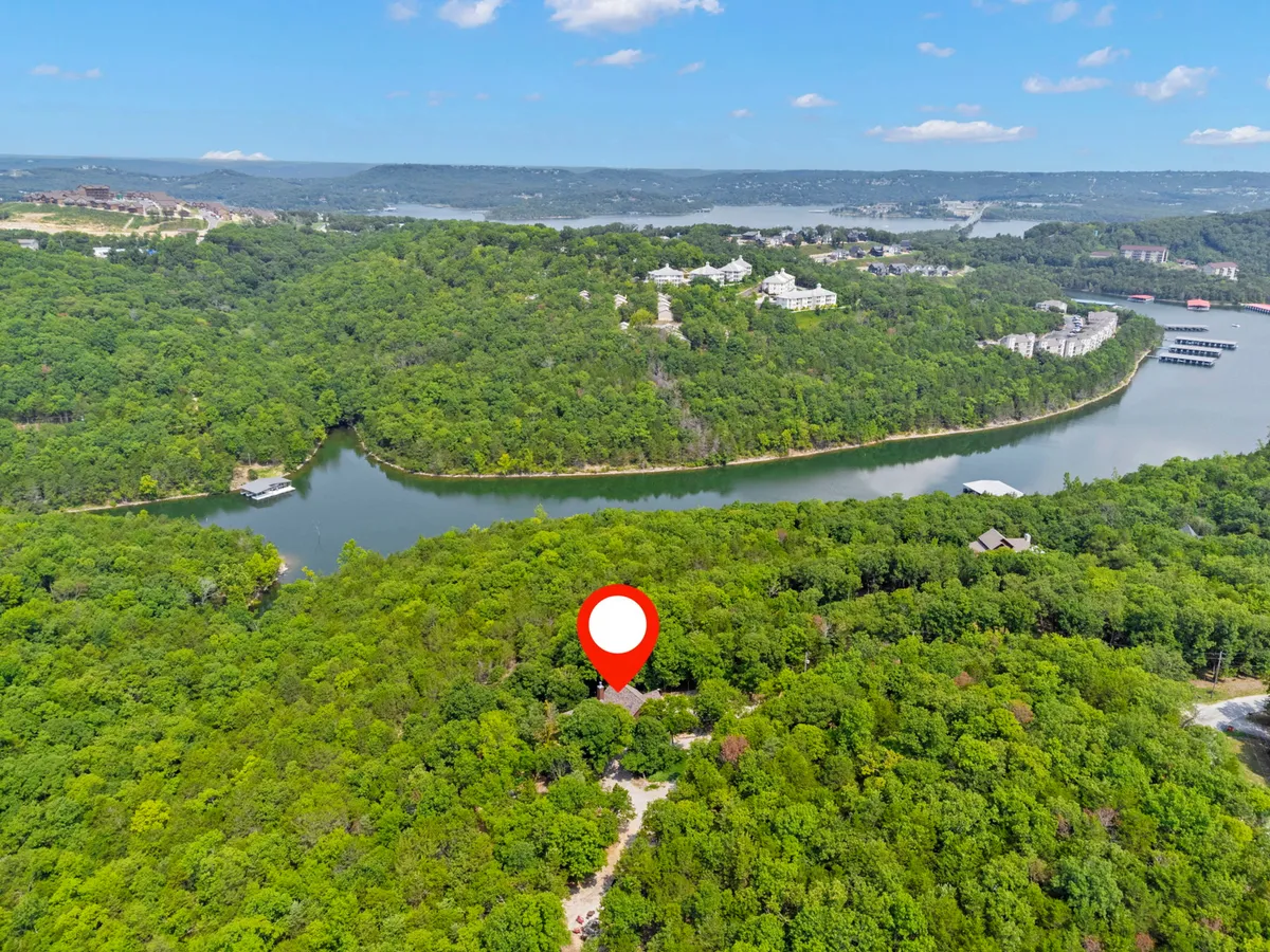 A panoramic view of a lush forest with a meandering river, distant homes, and a marked property location. This image conveys the sense of adventure and exploration unique to the Table Rock Lake and Ozarks area, illustrating opportunities for hiking, boating, and wildlife encounters throughout the seasons.
