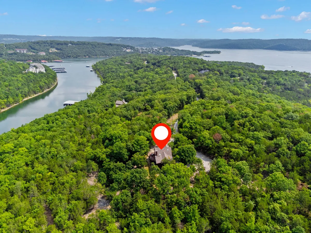 A landscape featuring lush green trees and a winding river, with a marker indicating the property location. The wide view captures the broader outdoor setting, suggesting nearby hiking and boating possibilities and offering context for the property's placement in nature.
